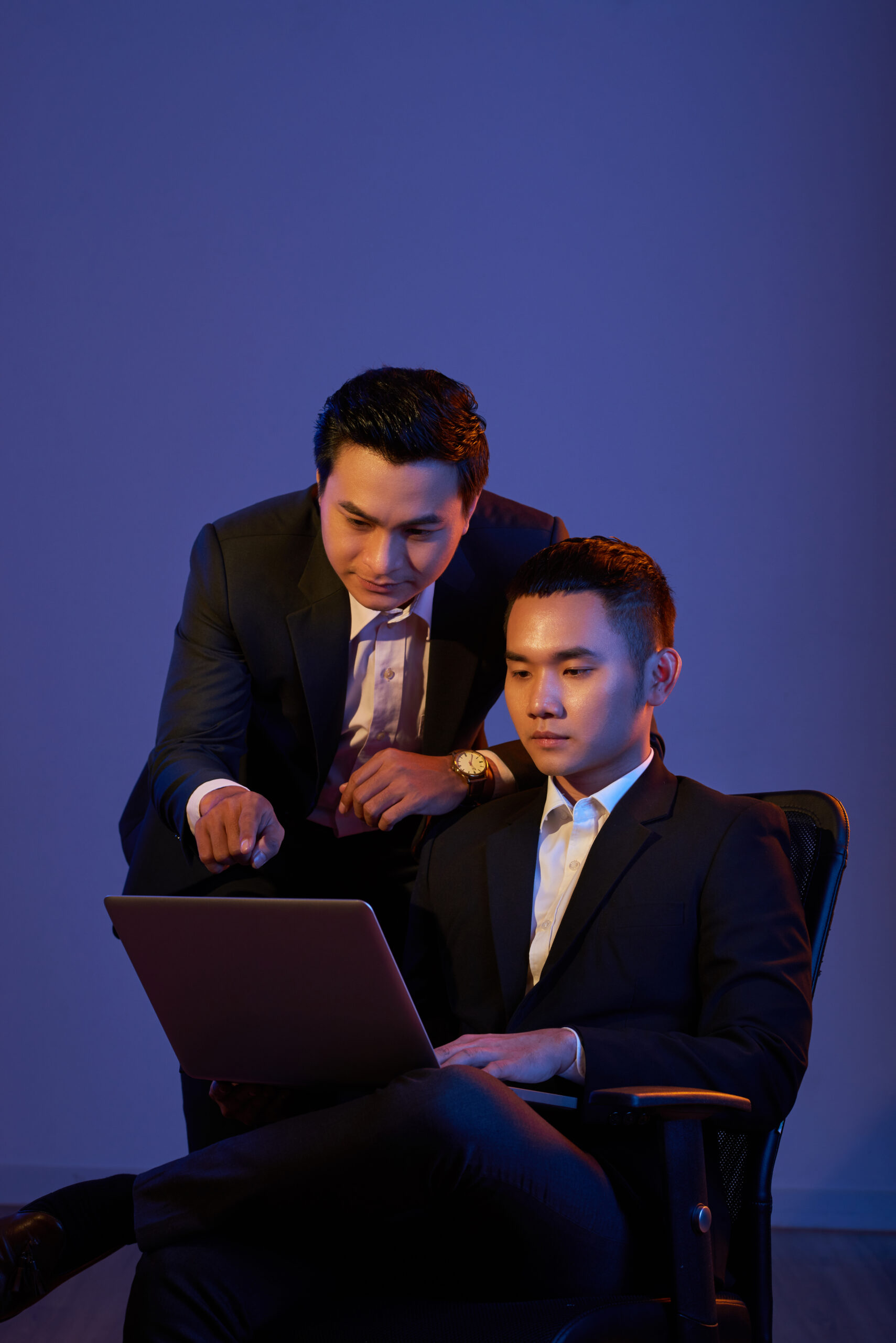 Young Vietnamese coworkers analyzing information on laptop screen